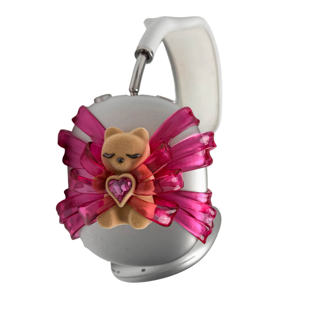 Ribbon Gummy Bear AirPods Max cover in Pink Edition, featuring a beige bear holding a pink crystal heart, surrounded by layered metallic pink ribbons.