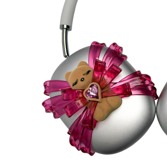 Ribbon Gummy Bear AirPods Max cover in Pink Edition, featuring a beige bear holding a pink crystal heart, surrounded by layered metallic pink ribbons.