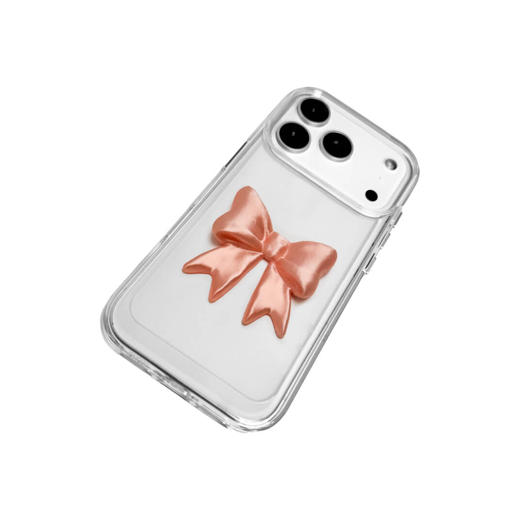 The Matte Bow iPhone Case S collection featuring the 3D sculpted matte bow in both Peach-Blush (Salmon Pink) and Classic White color variants, shown on both the Crystal Clear (Transparent) and White Leather Texture base options.