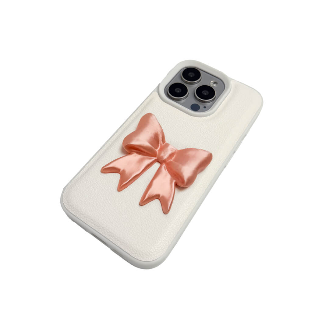 The Matte Bow iPhone Case S collection featuring the 3D sculpted matte bow in both Peach-Blush (Salmon Pink) and Classic White color variants, shown on both the Crystal Clear (Transparent) and White Leather Texture base options.