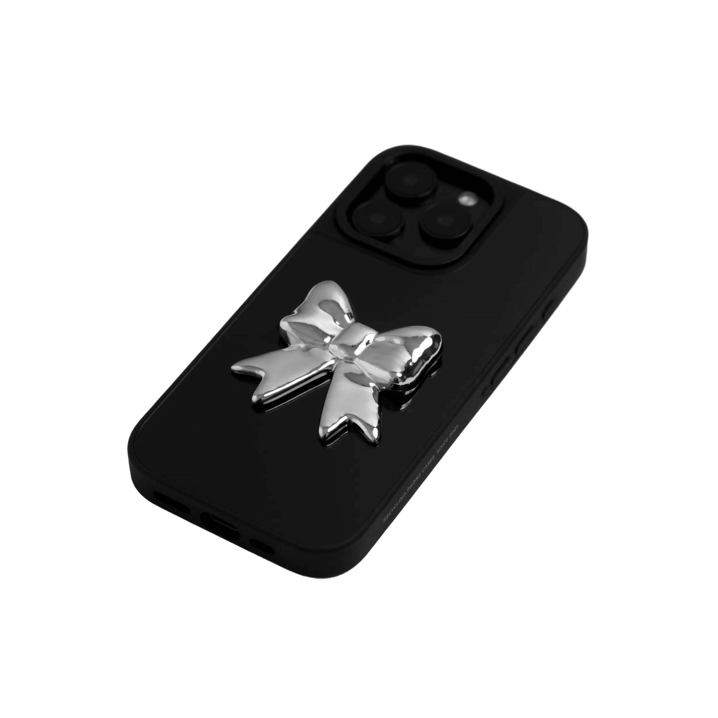A collection of four black iPhone cases, each adorned with a distinct silver 3D metal emblem: a prominent bow tie, a sleek circular stud, an intricate spider, and a stylized four-point cross.