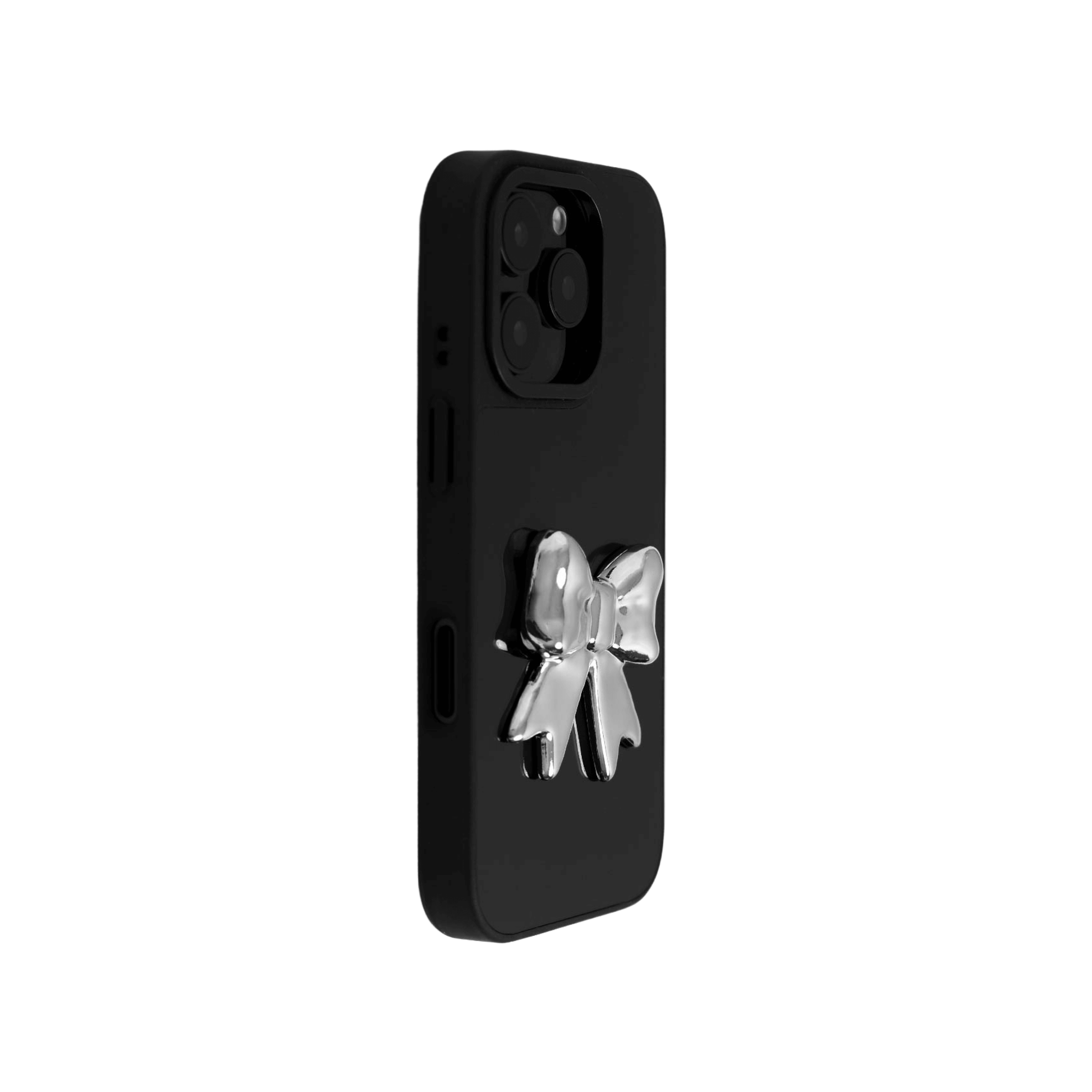 A collection of four black iPhone cases, each adorned with a distinct silver 3D metal emblem: a prominent bow tie, a sleek circular stud, an intricate spider, and a stylized four-point cross.