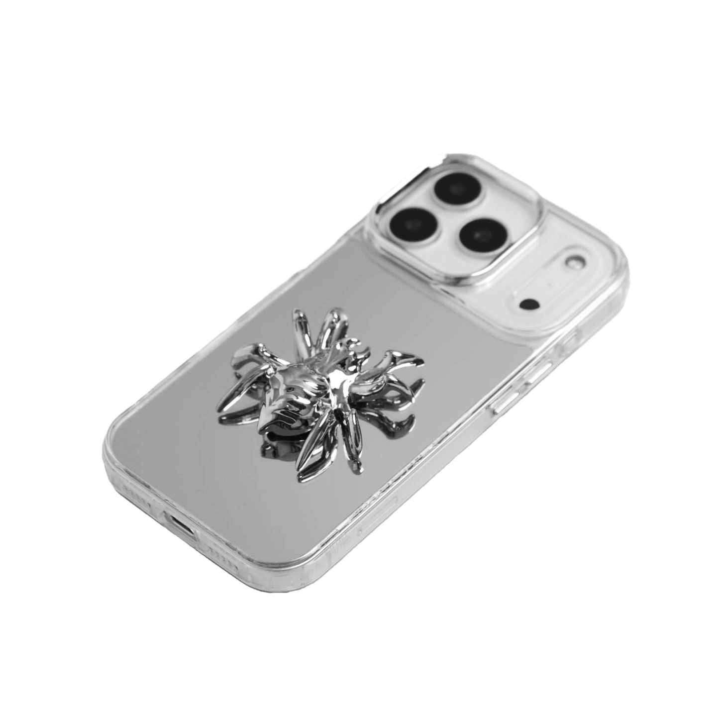 A collection of four black iPhone cases, each adorned with a distinct silver 3D metal emblem: a prominent bow tie, a sleek circular stud, an intricate spider, and a stylized four-point cross.