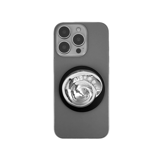 Glossy silver, white spiral shell phone grip with rhinestone accents – mounted on a matte black base and attached to a gray iPhone case