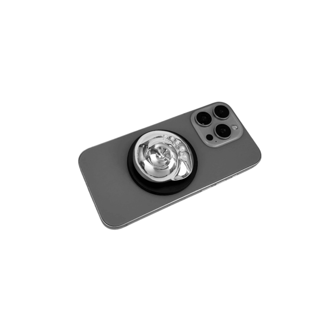 Glossy silver, white spiral shell phone grip with rhinestone accents – mounted on a matte black base and attached to a gray iPhone case
