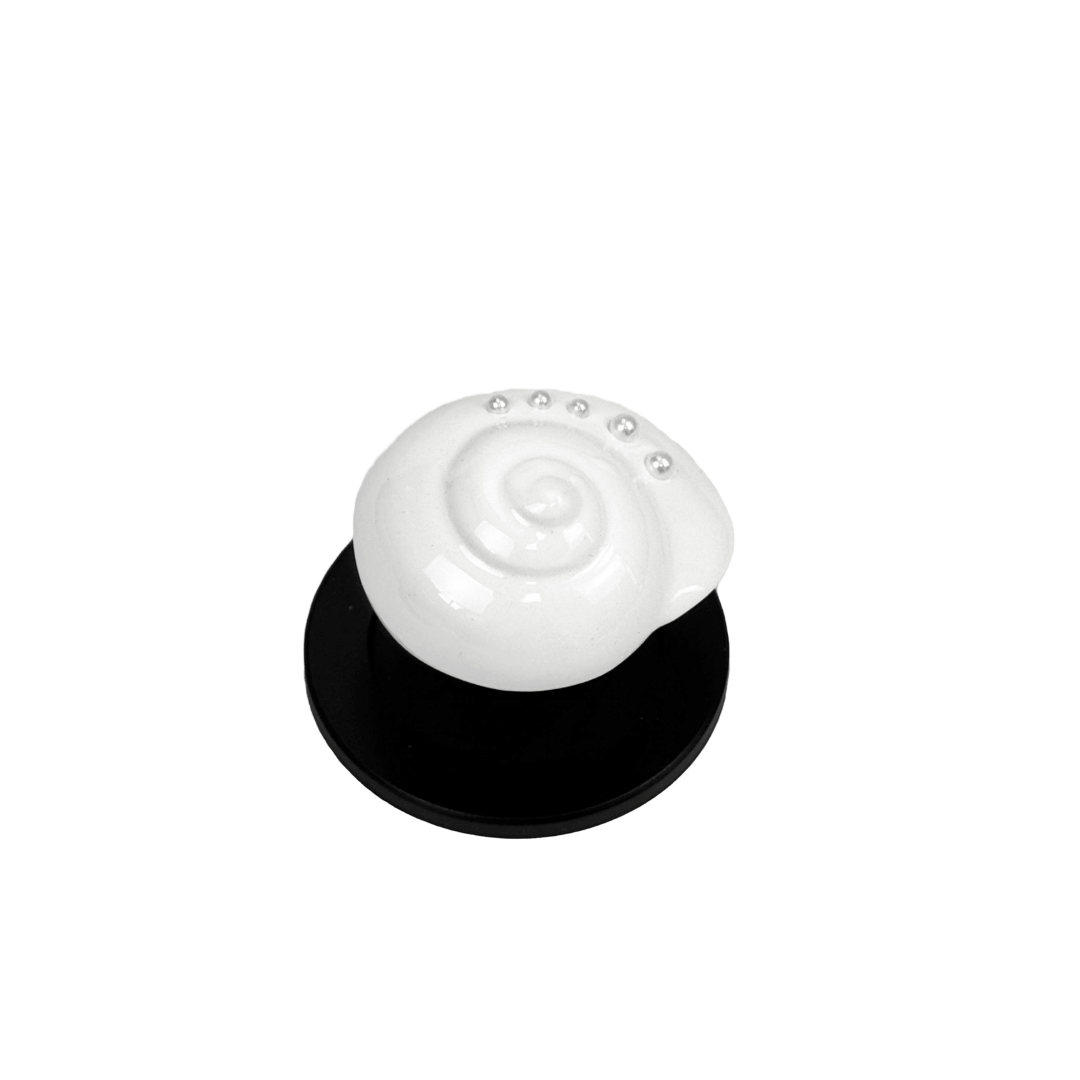 Glossy silver, white spiral shell phone grip with rhinestone accents – mounted on a matte black base and attached to a gray iPhone case