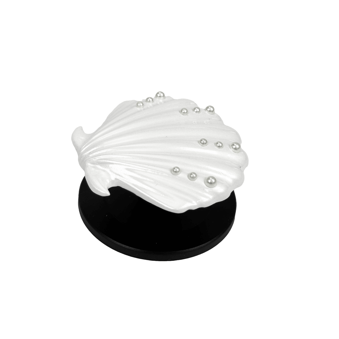 Gradient silver, white and yellow-to-pink scallop shell phone grip with rhinestone accents, mounted on a black base and attached to a gray iPhone case