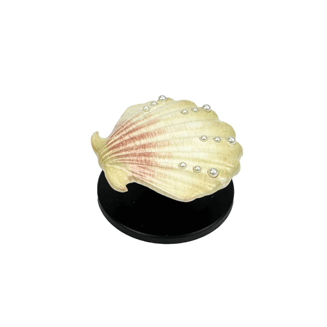 Gradient silver, white and yellow-to-pink scallop shell phone grip with rhinestone accents, mounted on a black base and attached to a gray iPhone case