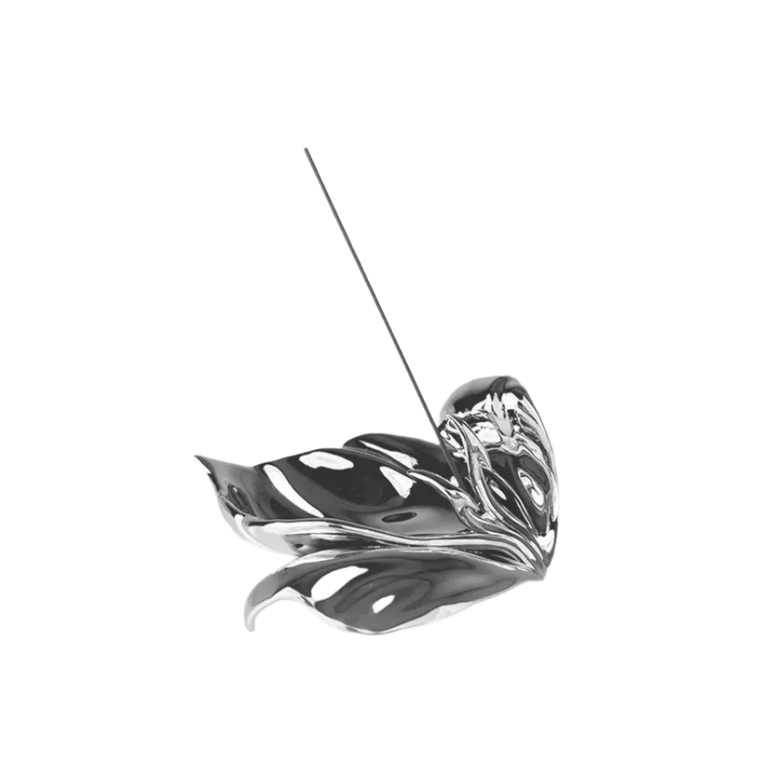Futuristic chrome incense holder with flowing petal silhouette – organic metallic design cradling incense stick in sculptural bloom