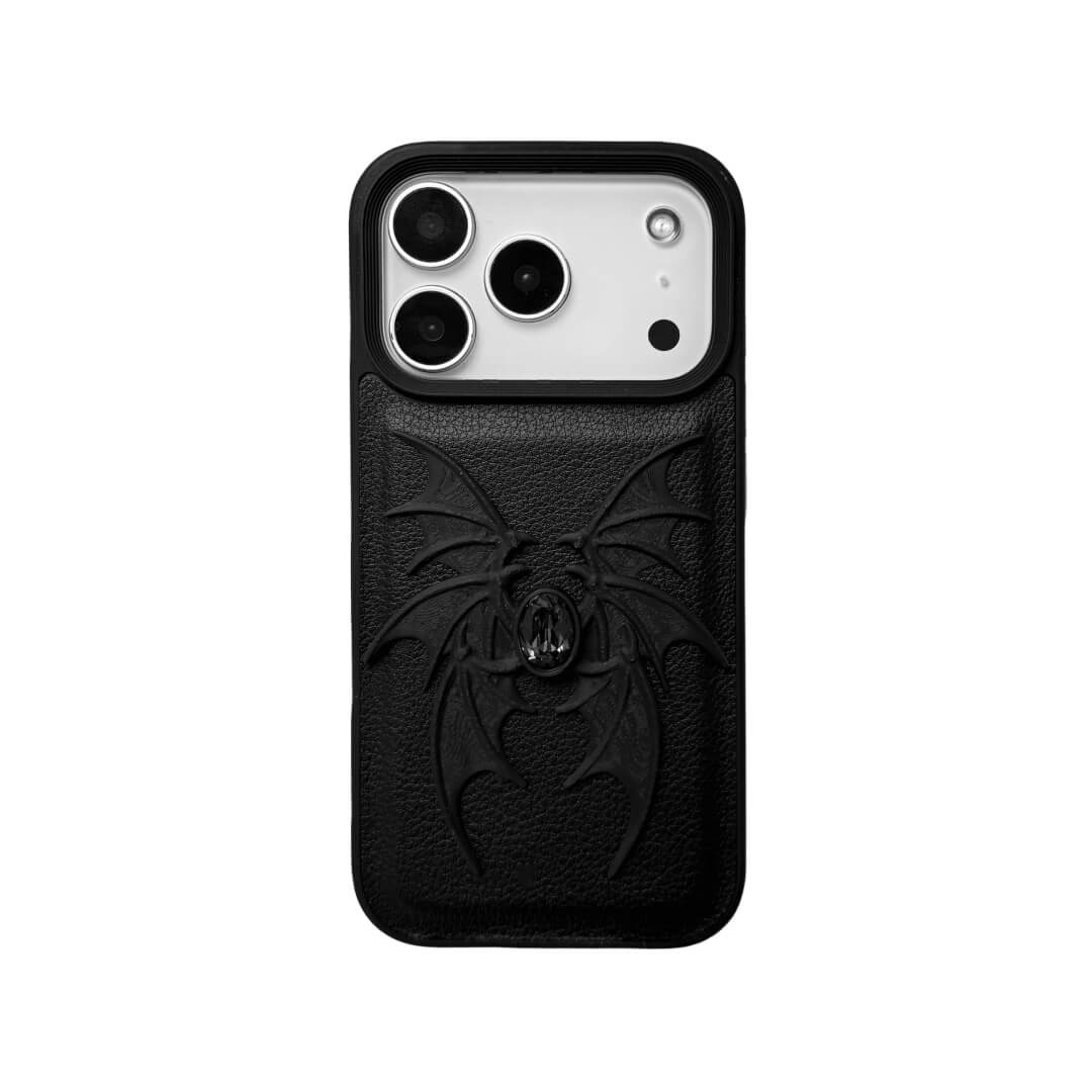 A high-concept iPhone case featuring a 3D-printed quad-wing demon design in a natural matte black finish, centered with a sparkling black Swarovski crystal. The design is shown on a Clear Transparent base and a Black Litchi Leather textured base, highlighting the intricate, layered skeletal wing structure and the dark gemstone detail.