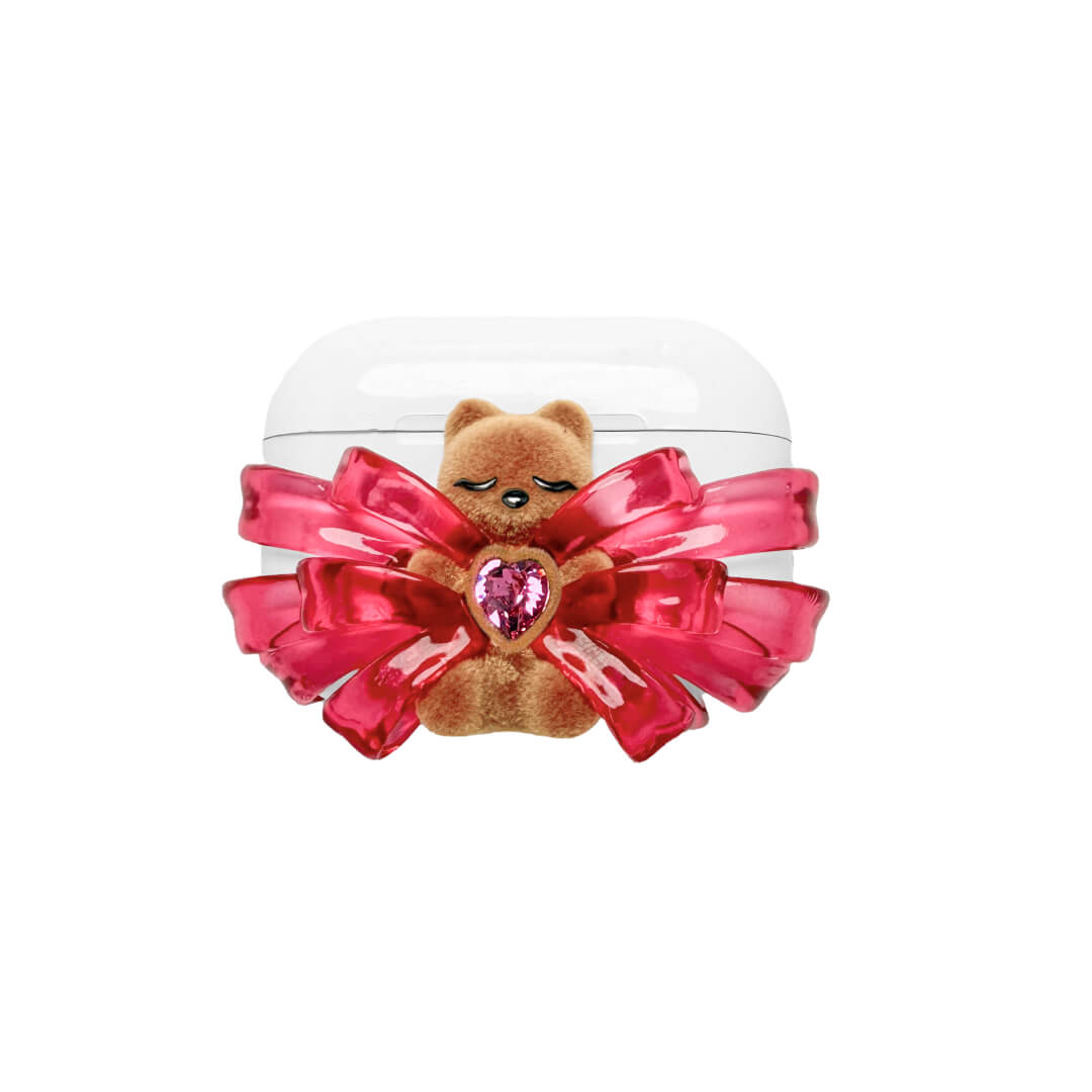 Ribbon Magic Bear AirPods Cover featuring a beige gummy bear with closed eyes, holding a pink crystal heart, framed by layered translucent pink ribbons.