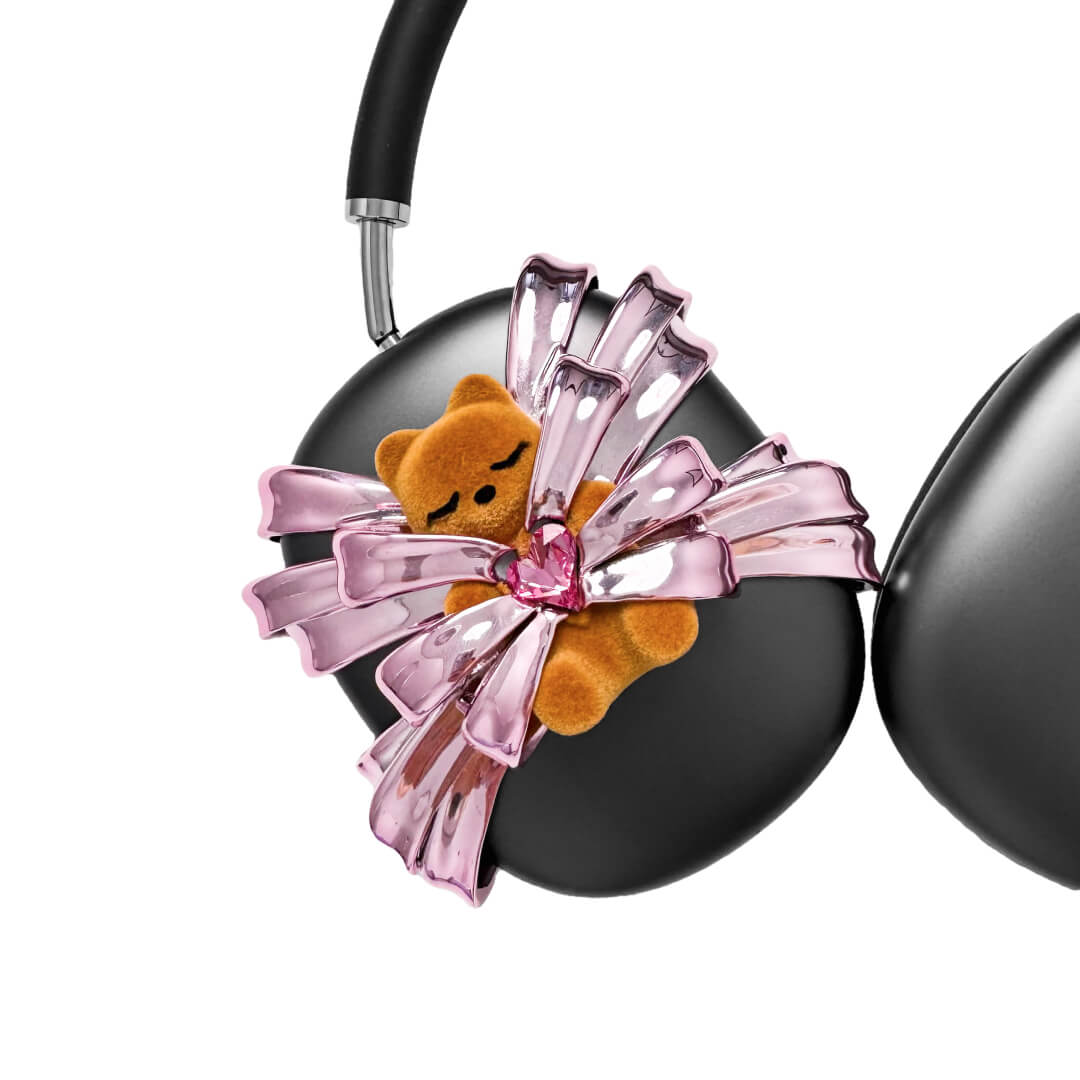 Ribbon Gummy Bear AirPods Max cover in Pink Edition, featuring a beige bear holding a pink crystal heart, surrounded by layered metallic pink ribbons.