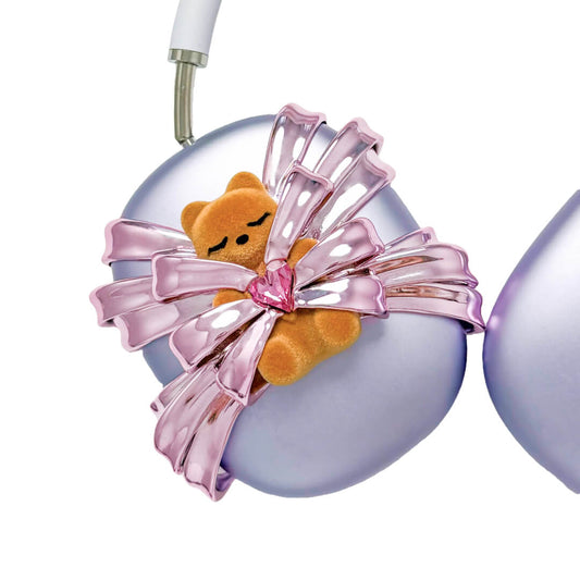 Ribbon Gummy Bear AirPods Max cover in Pink Edition, featuring a beige bear holding a pink crystal heart, surrounded by layered metallic pink ribbons.