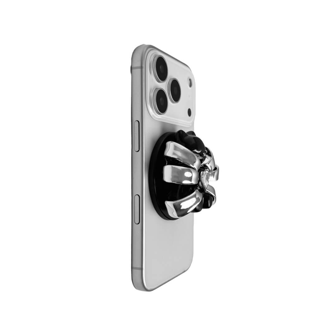 Ribbon Magic Bear Phone Grip in Pink Edition featuring a glossy pink ribbon with a beige gummy bear at the center, holding a sparkling pink heart-shaped crystal.