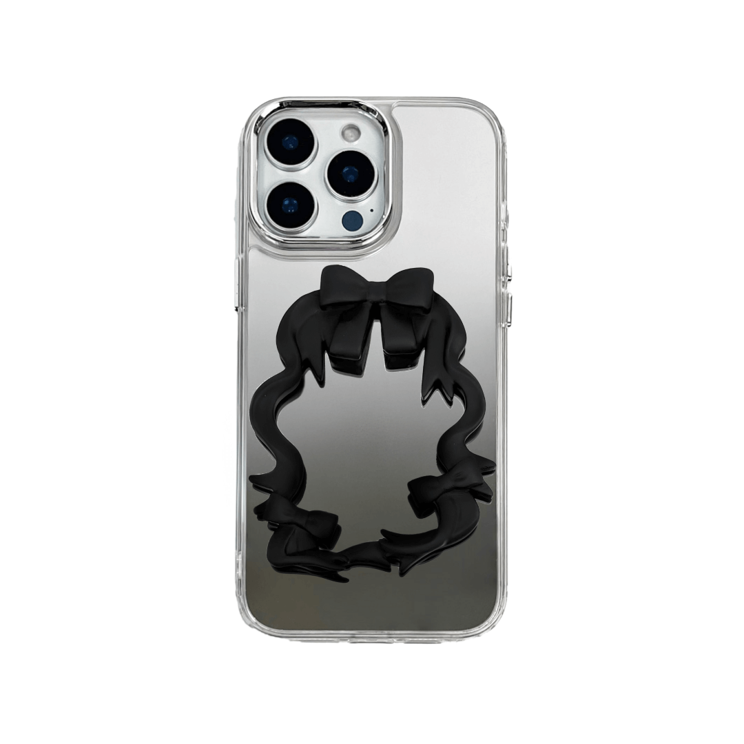 Mirror phone case with sculpted pink, silver, black and white bows and ribbon frame design, creating a romantic, soft-glam look.