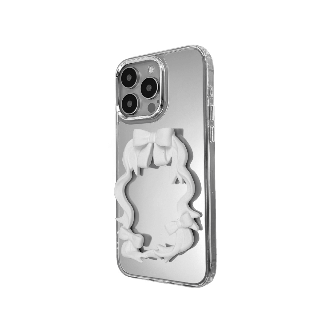 Mirror phone case with sculpted pink, silver, black and white bows and ribbon frame design, creating a romantic, soft-glam look.