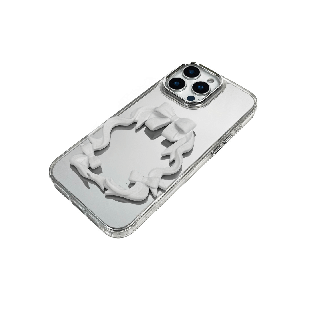 Mirror phone case with sculpted pink, silver, black and white bows and ribbon frame design, creating a romantic, soft-glam look.
