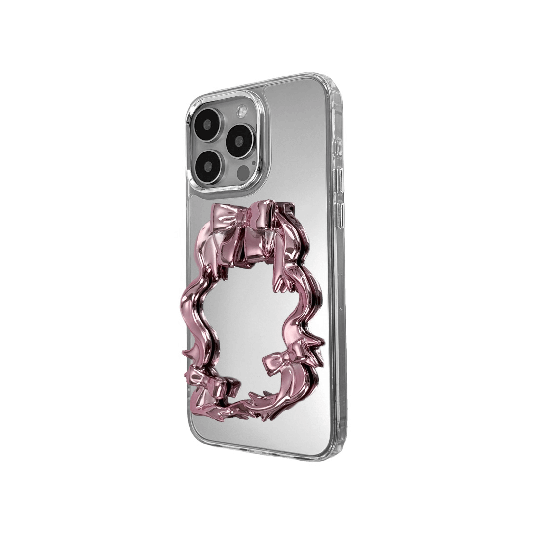 Mirror phone case with sculpted pink, silver, black and white bows and ribbon frame design, creating a romantic, soft-glam look.