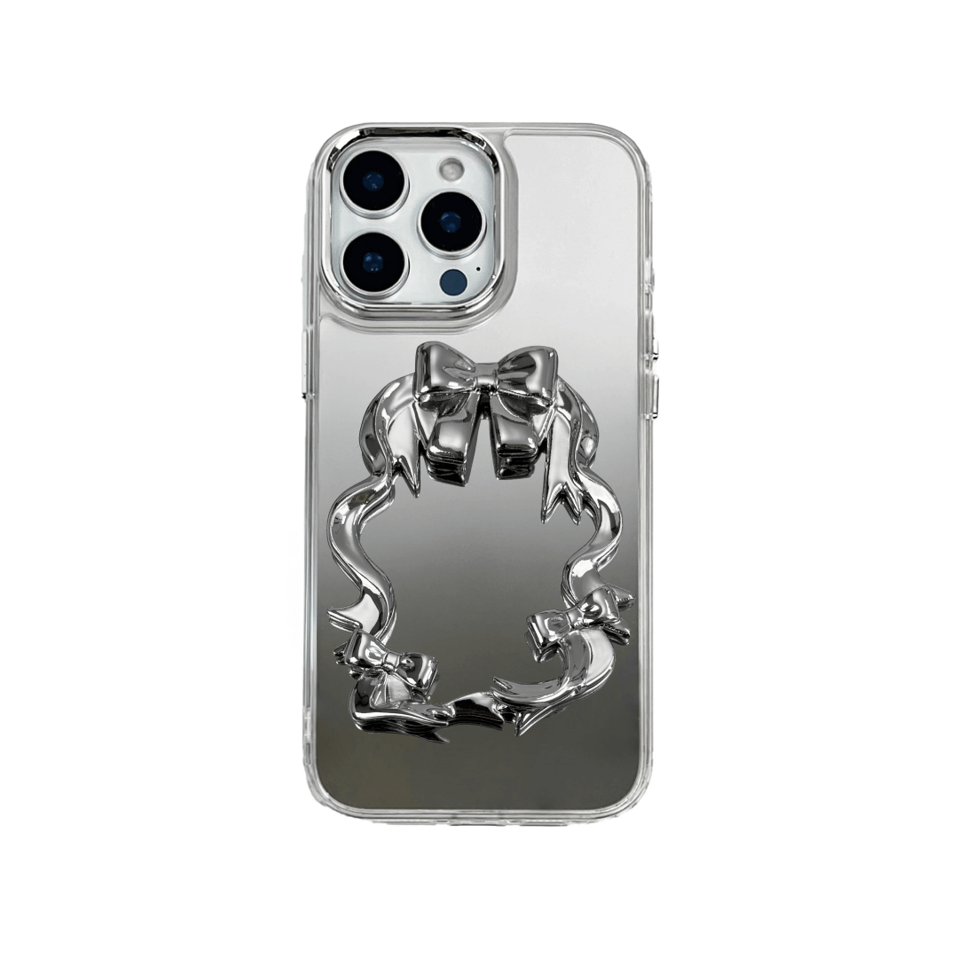 Mirror phone case with sculpted pink, silver, black and white bows and ribbon frame design, creating a romantic, soft-glam look.