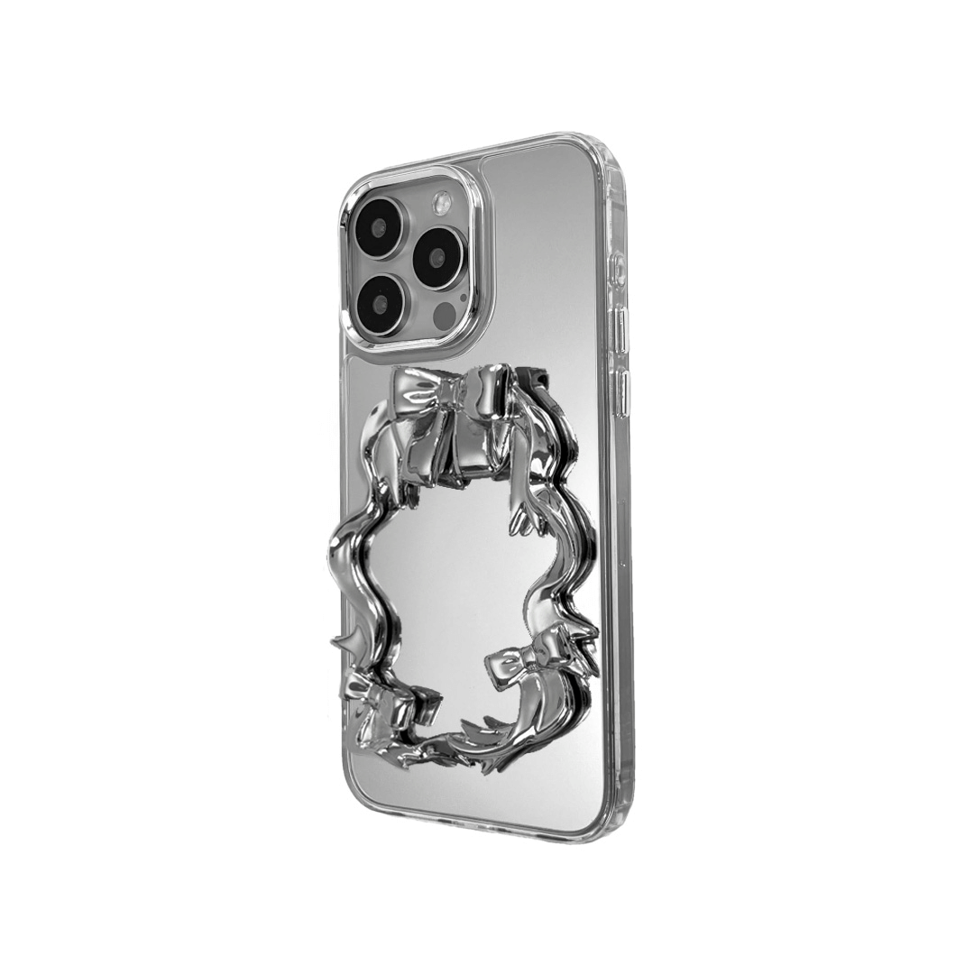 Mirror phone case with sculpted pink, silver, black and white bows and ribbon frame design, creating a romantic, soft-glam look.