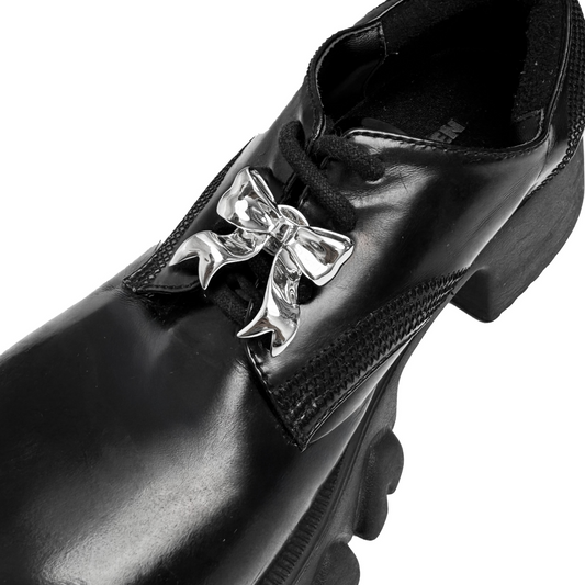 A silver metallic silken ribbon shoelace charm with flowing curves, giving a graceful and delicate accent to sneakers.