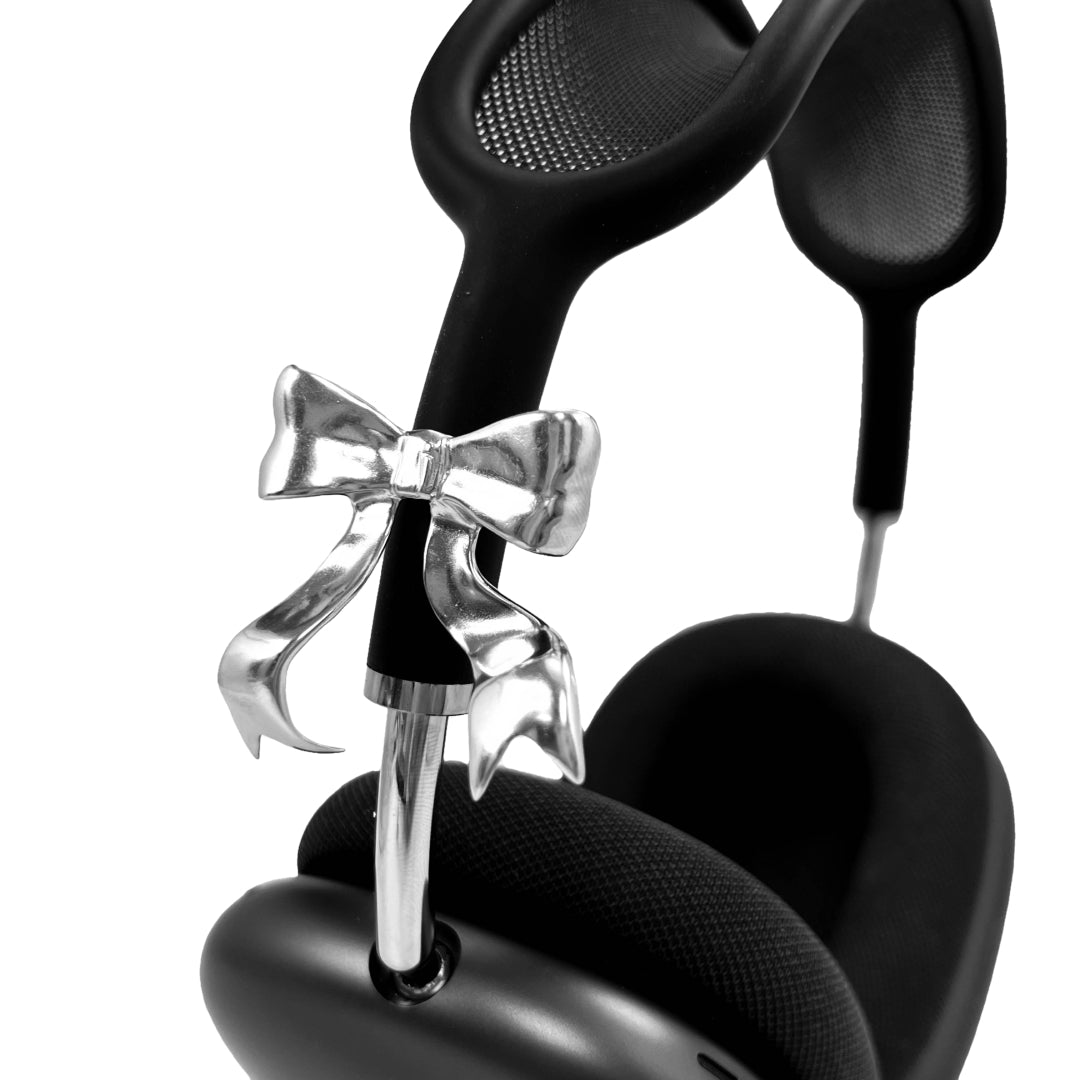 Polished silver bow-shaped accessory attached to the side of black AirPods Max headphones.