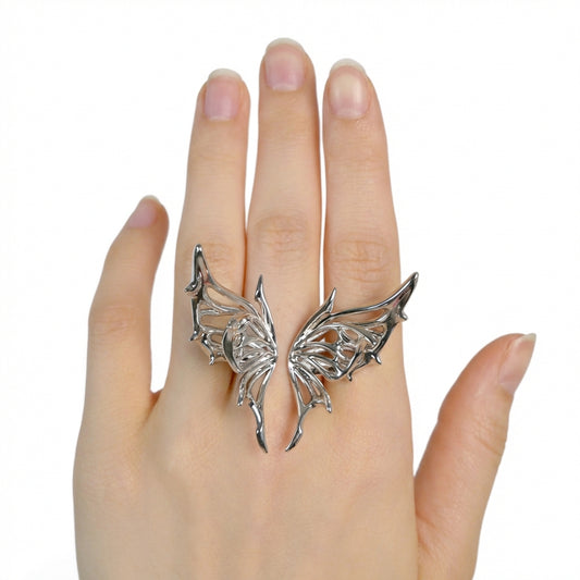 Silver angel wing ring on a hand against a white background