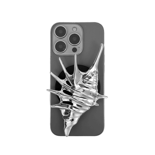 Matte silver, white and yellow spiked conch shell phone grip with sculptural spikes and spiral ridges, mounted on a black base and attached to a gray iPhone case.