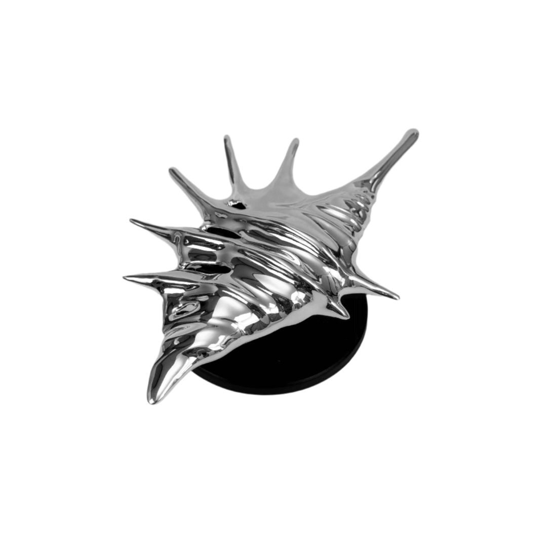 Matte silver, white and yellow spiked conch shell phone grip with sculptural spikes and spiral ridges, mounted on a black base and attached to a gray iPhone case.
