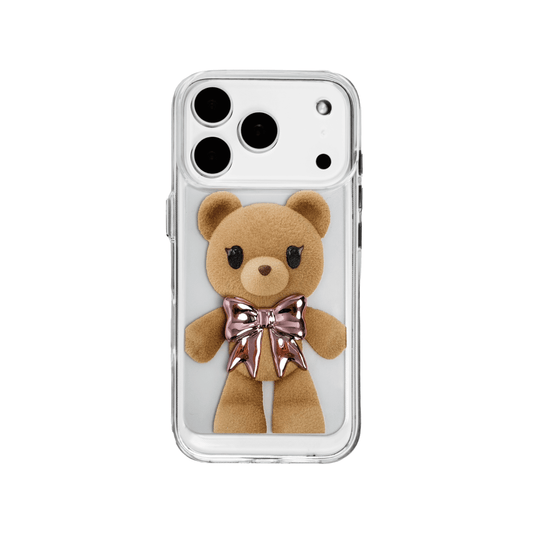A clear iPhone case featuring an illustration of a standing brown teddy bear wearing a pink metallic bow tie. The case is transparent, allowing the phone's color to show through.