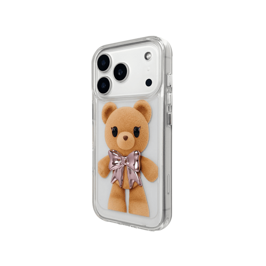 A clear iPhone case featuring an illustration of a standing brown teddy bear wearing a pink metallic bow tie. The case is transparent, allowing the phone's color to show through.