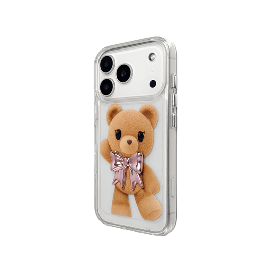 A clear iPhone case featuring an illustration of a standing brown teddy bear wearing a pink metallic bow tie. The case is transparent, allowing the phone's color to show through.
