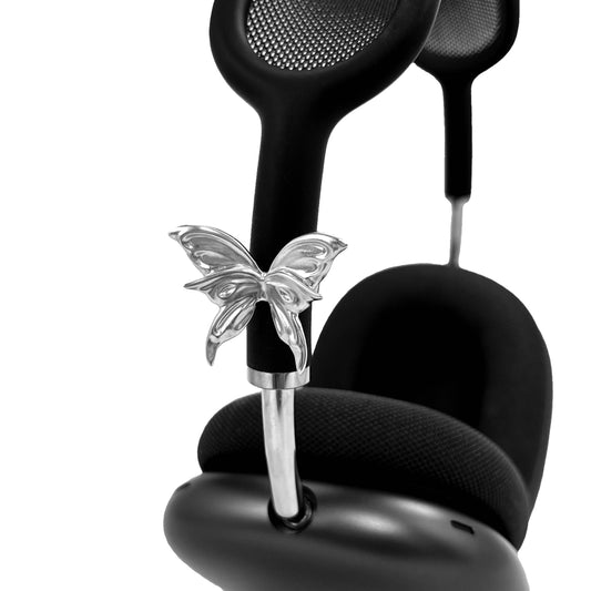 Chrome butterfly-shaped decorative accessory attached to AirPods Max.
