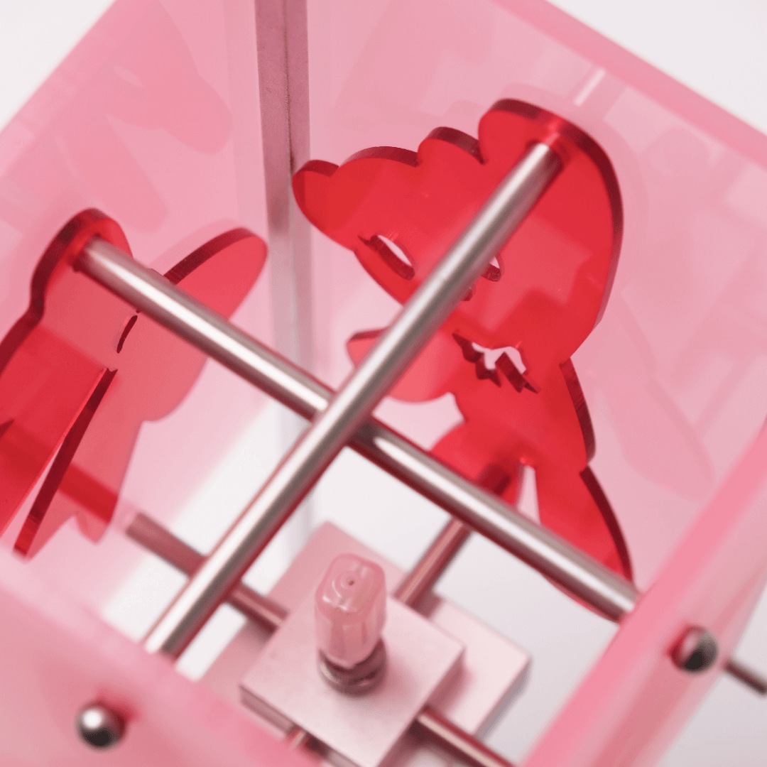 Close-up of a pink clock with red heart shapes and metal hands.
