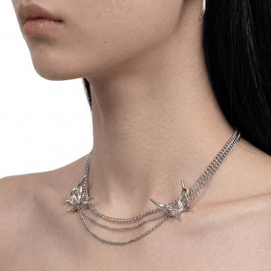 Silver necklace with intricate designs on a model against a neutral background