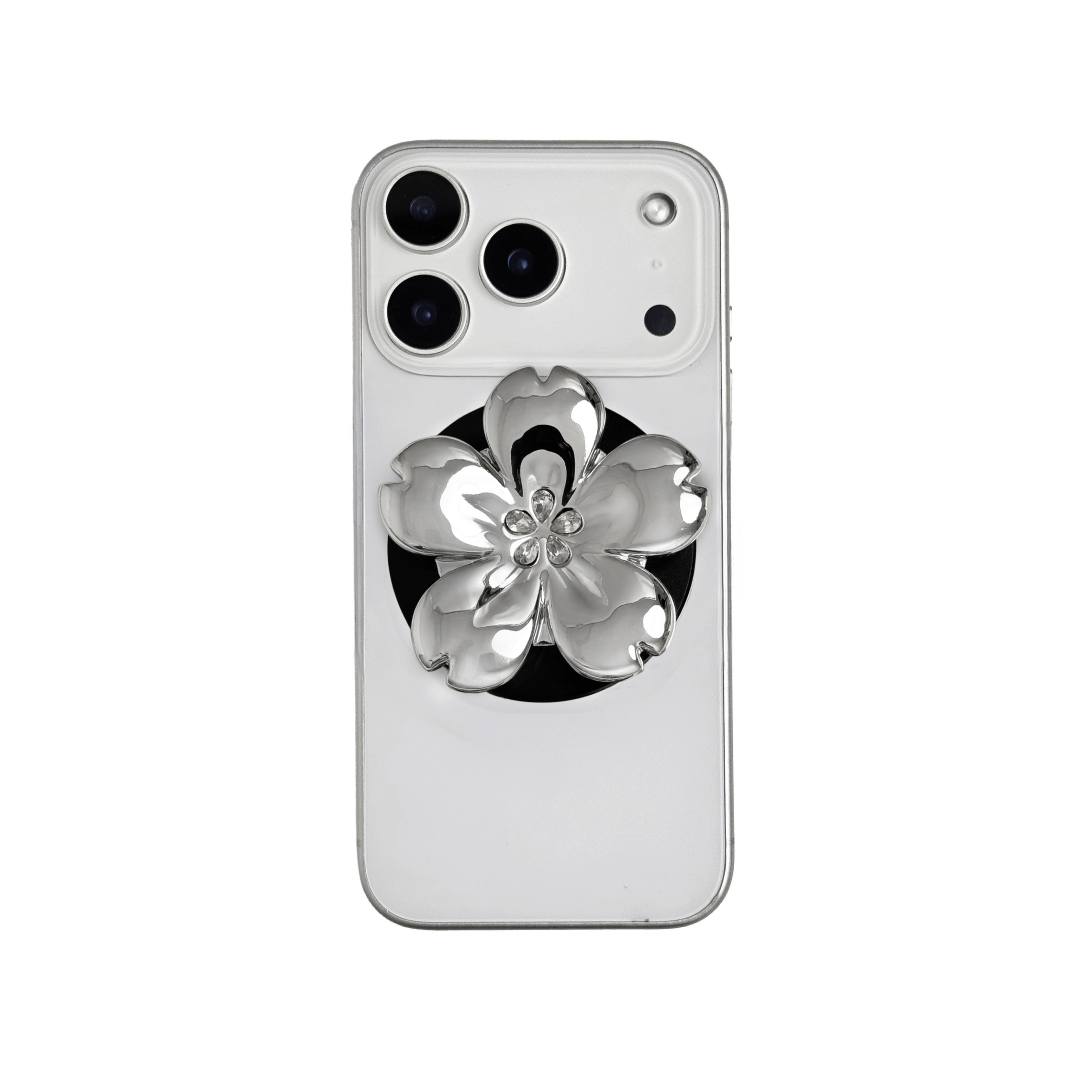 Magnetic phone grip with a silver mirror finish, decorated with a cherry blossom in pink or silver tones accented by five sparkling crystals for a luxurious, floral-inspired look.