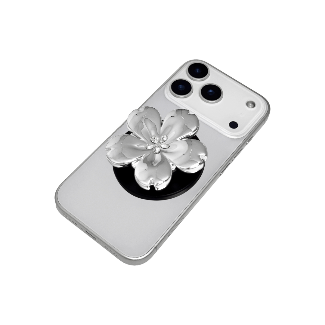 Magnetic phone grip with a silver mirror finish, decorated with a cherry blossom in pink or silver tones accented by five sparkling crystals for a luxurious, floral-inspired look.