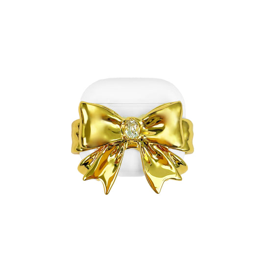 airpods cover, gem, bow, gold, white, xtended identity: Luxurious golden bow-shaped AirPods case featuring a central Swarovski crystal, 18K platinum plated metallic finish, high-end coquette tech accessory.中央にスワロフスキークリスタルを配した豪華なゴールドリボン型AirPodsケース。18Kプラチナメッキ仕上げのメタリックな輝き。