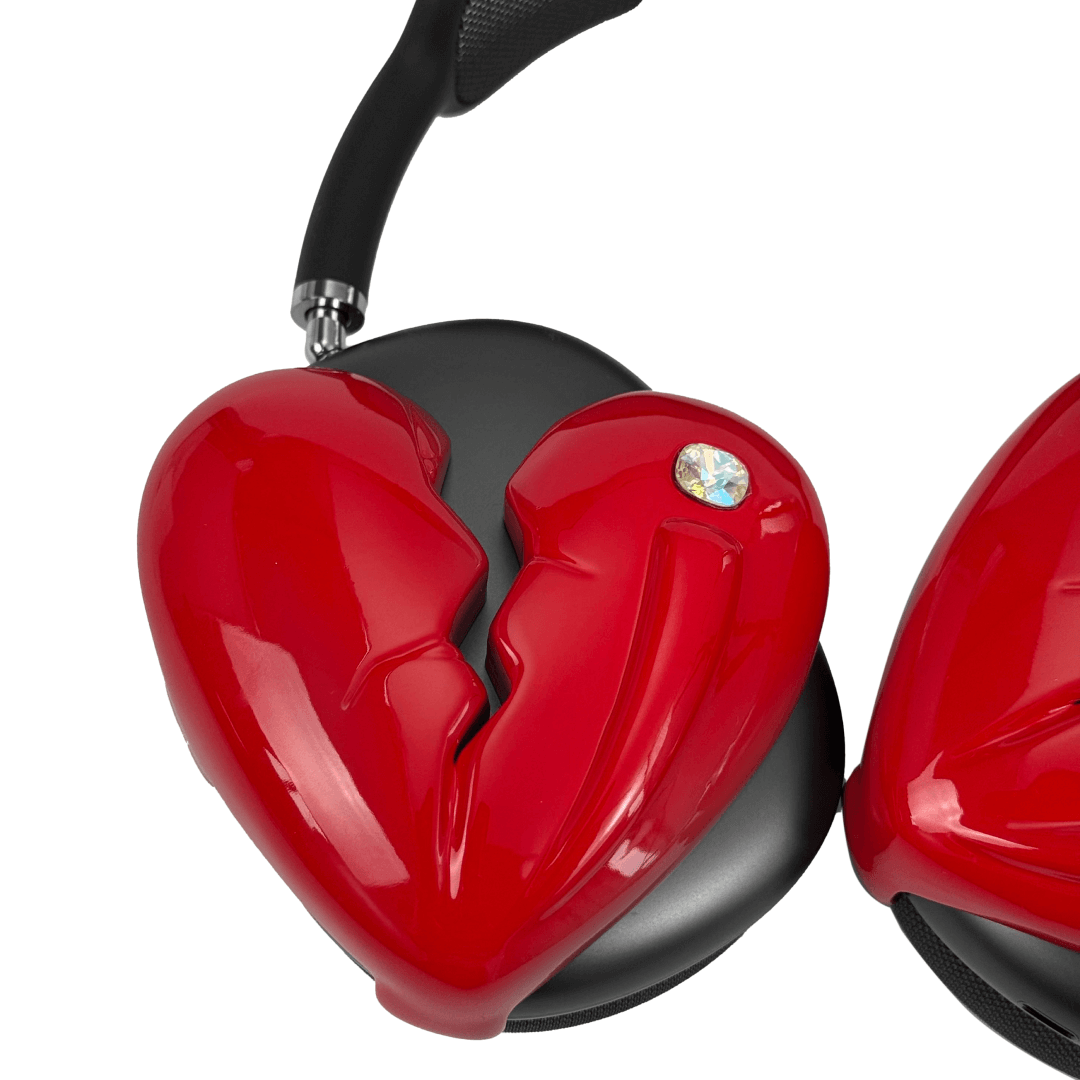 Silver, pink, red and black AirPods Max cover featuring a metallic broken heart design, with a sculpted crack down the center and small embedded crystal detail.