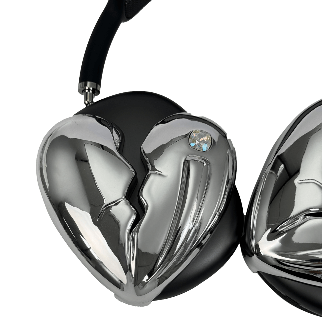 Silver, pink, red and black AirPods Max cover featuring a metallic broken heart design, with a sculpted crack down the center and small embedded crystal detail.