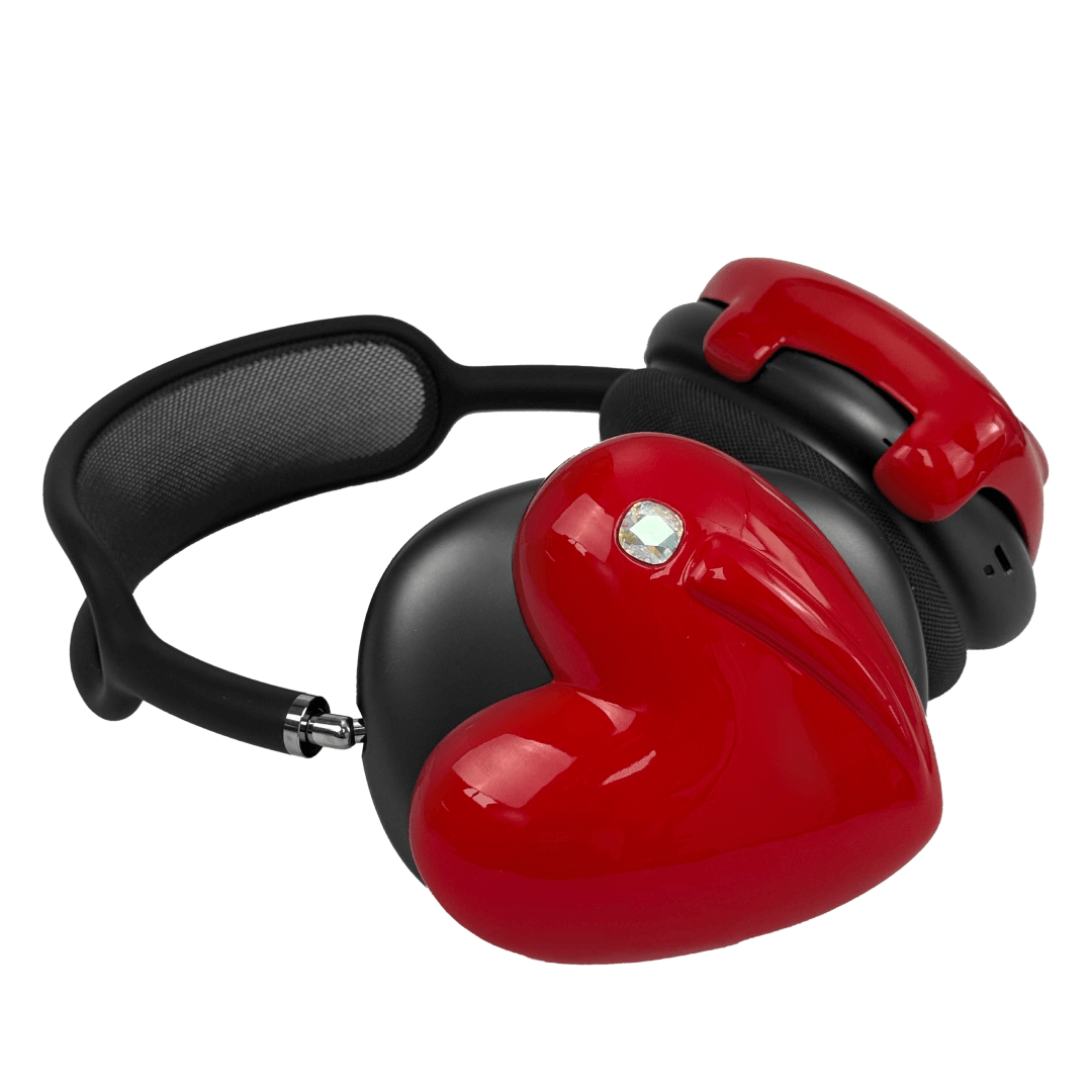 Metallic heart-shaped AirPods Max cover in silver, pink, red and black, with a smooth 3D sculpted surface and a single crystal stud detail.