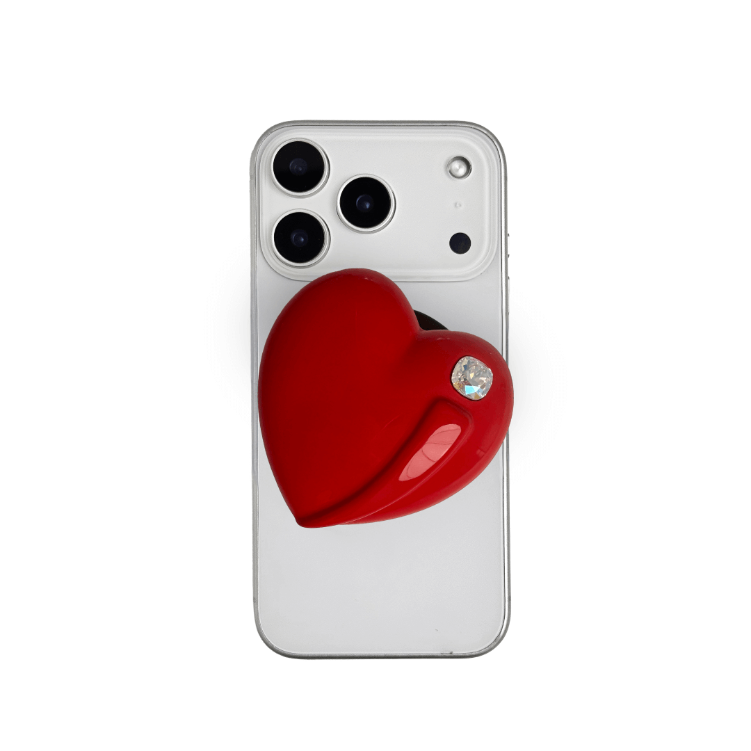 Metallic silver, pink, red, black Phone grip with a large sculpted heart in 3D, featuring a shiny chrome finish and a single gem-like detail.