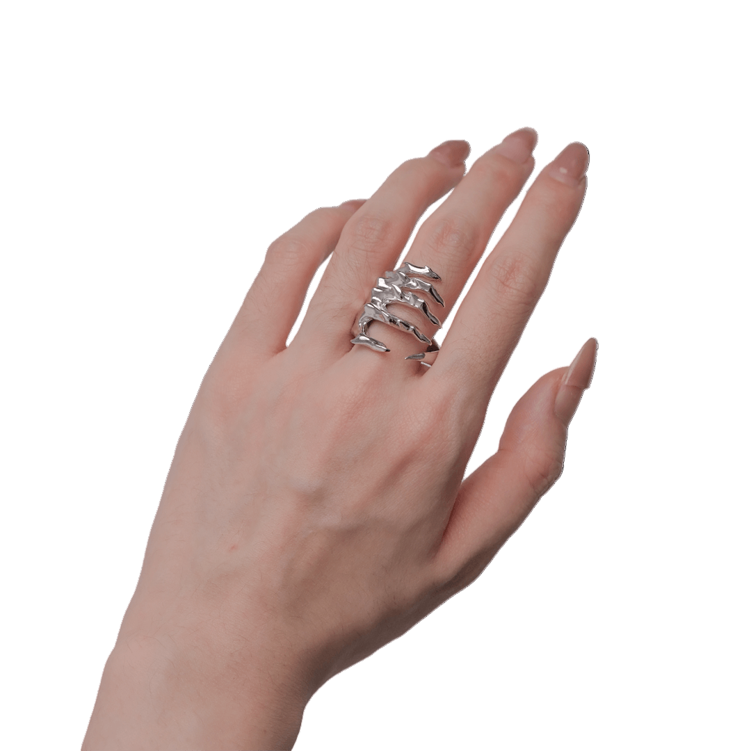 Hand wearing a stack of silver rings on a black background